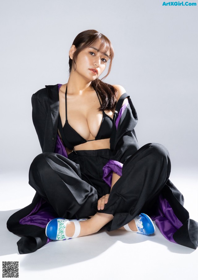 A woman in a black top and black pants sitting on the ground.