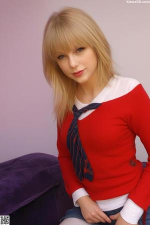 A woman in a blue sweater sitting on a bed.