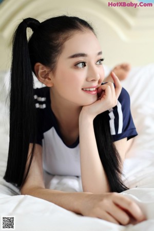 A woman in a white and blue bikini posing on a bed.