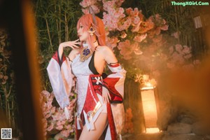 A woman in a kimono standing in front of a flowering tree.