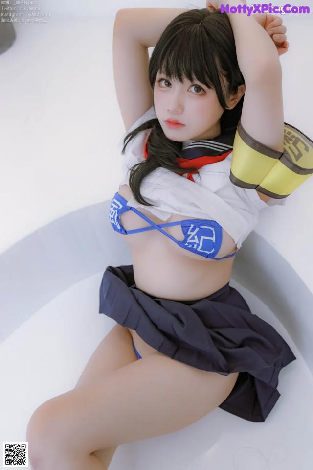 A woman in a blue and white outfit sitting in a bathtub.