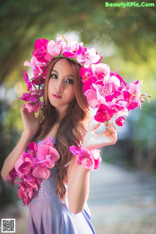 A woman in a blue dress holding a bunch of pink flowers.