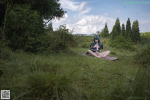 A woman with blue hair is sitting on a blanket.