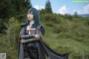 A woman with blue hair is posing in a field.