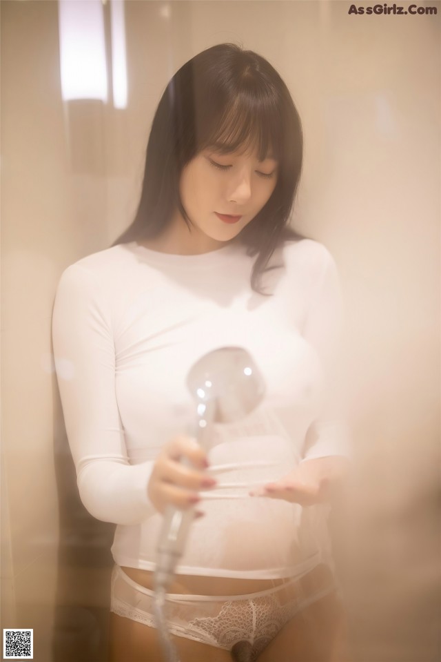 A woman in a white shirt holding a light bulb.