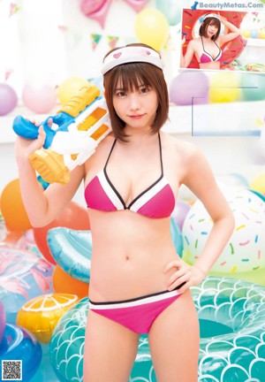 A woman in a bikini standing next to an inflatable donut.