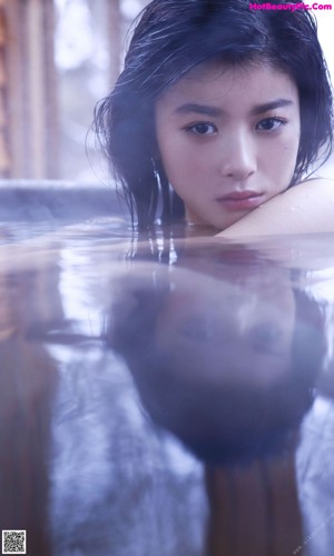 A young woman laying in a pool of water.
