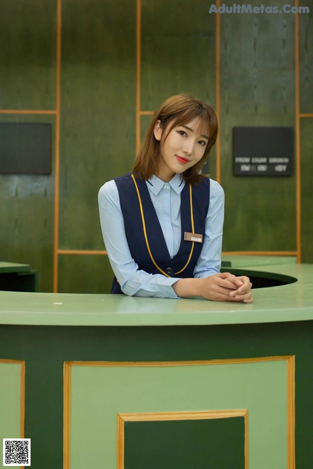 A woman sitting at a desk in a hotel lobby.