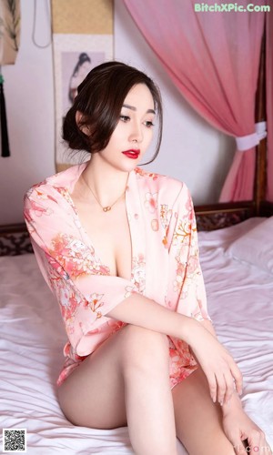 A woman laying on top of a bed in a pink dress.