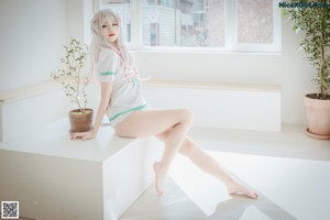 A woman sitting on a bed with her legs crossed.