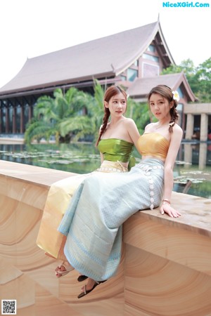 A couple of women sitting next to each other near a pool.