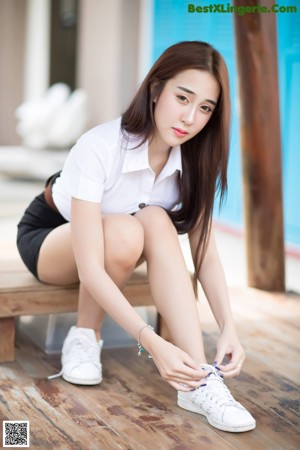 A woman sitting on top of a wooden bench.