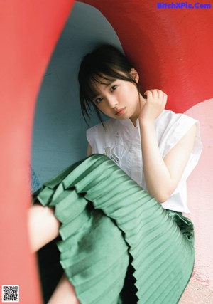 A young girl in a yellow dress sitting on the ground.