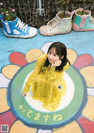 A woman sitting on the ground next to a sign.