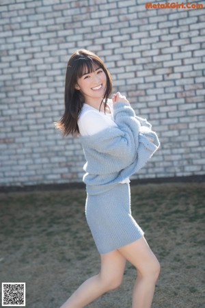 A woman wearing a gray hooded sweater and smiling.