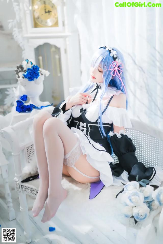 A woman sitting on a white chair with blue hair.