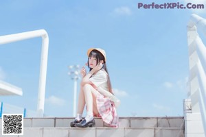 A woman sitting on the steps of a building holding a lollipop.