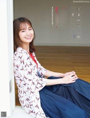 A woman in a blue top and white jacket posing for a picture.