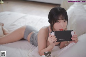 A woman laying on a bed playing a video game.
