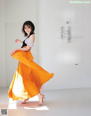 A woman sitting on the floor in a white dress.