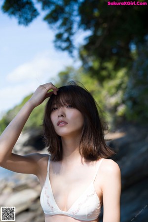 A woman in a white bikini standing on a rock.