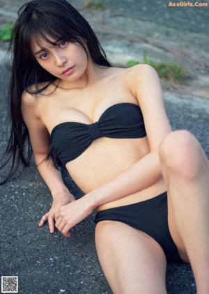 A woman in a blue bathing suit laying on a wooden floor.