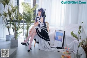 A woman in a maid outfit sitting on a chair.