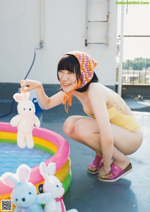 A woman sitting in an inflatable pool with stuffed animals.