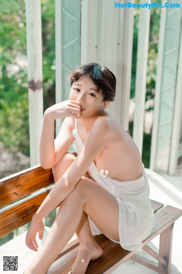 A woman sitting on a wooden bench with her legs crossed.