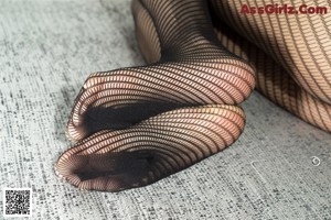 A pair of black fishnet stockings on a gray surface.