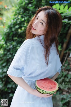 A woman holding a slice of watermelon in her hand.