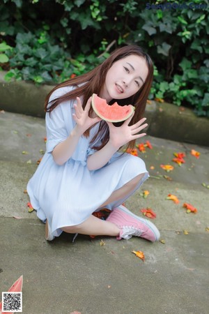A woman in a blue shirt is holding a plant.