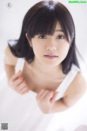 A woman in a white dress leaning against a wall.