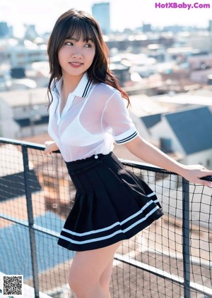 A woman in a white shirt and black shorts is posing on a bed.