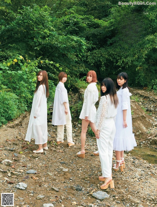 A group of women standing next to each other on a dirt road.