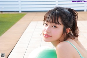 A woman laying on a pink yoga mat with a green ball.