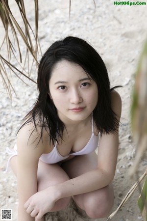 A woman sitting on the floor in front of a window.