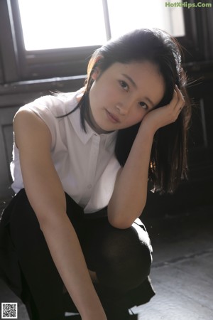 A woman leaning against a wall in a garden.