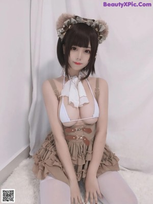 A woman in a white top and brown skirt sitting on a white rug.