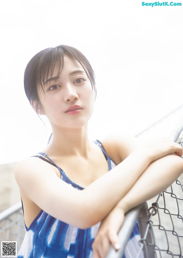 A woman leaning against a fence with her arms crossed.