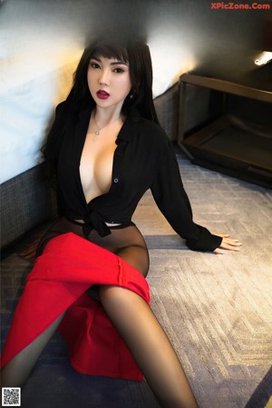 A woman in a black dress and high heels posing in a hotel room.