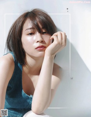 A woman with a ring on her finger is posing for a magazine.