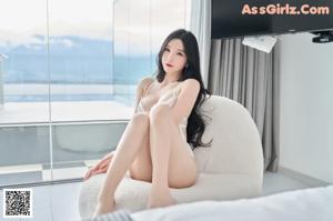 A woman in a white lingerie standing on a balcony.