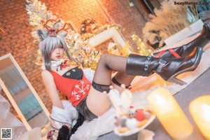 A woman sitting on the floor in front of a Christmas tree.