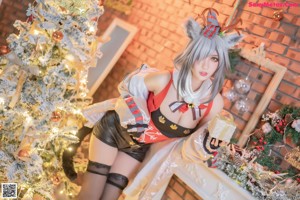 A woman in a red and white outfit posing in front of a Christmas tree.