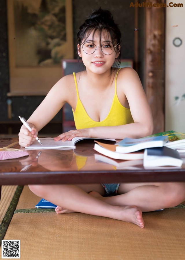 A woman sitting at a table writing in a notebook.