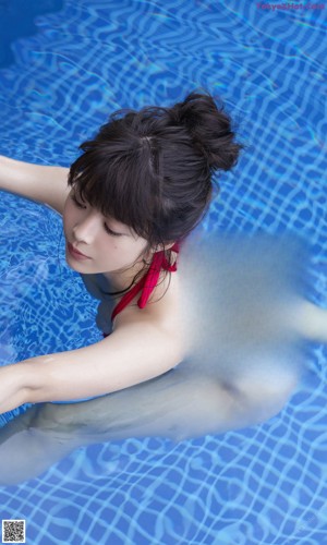 A woman laying on a bed in a blue bikini.