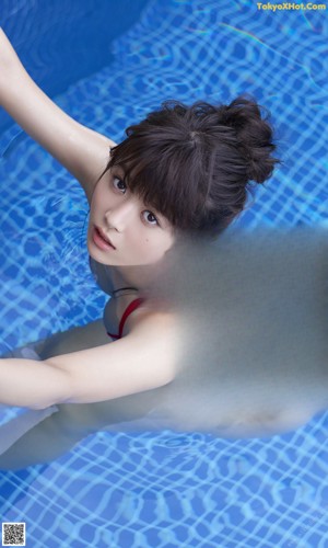 A woman in a red bikini standing next to a swimming pool.